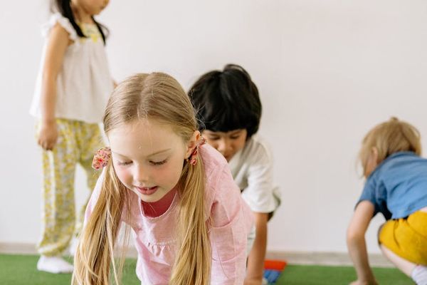 A diverse group of kids playfully stretching on colorful mats.